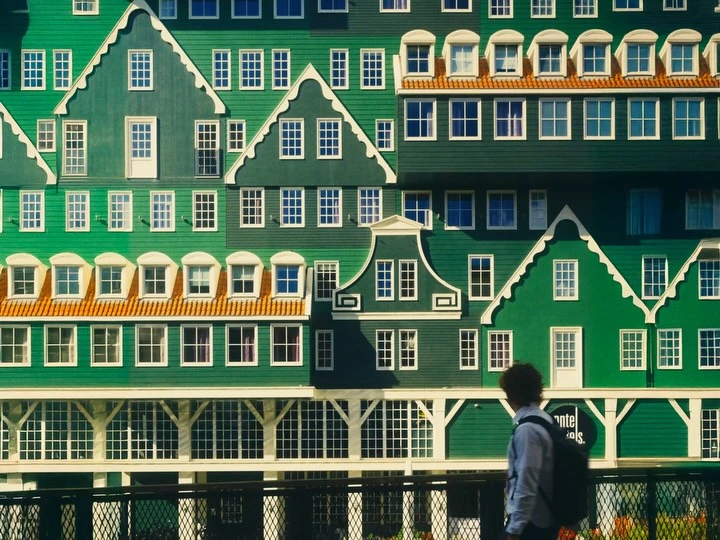 Green timber facades and white windows above a passer-by in Zaandam
