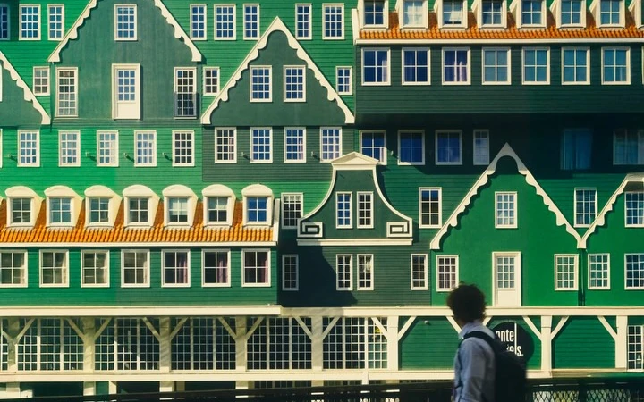 Green timber facades and white windows above a passer-by in Zaandam