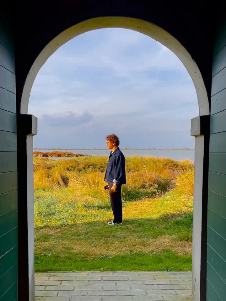 A figure framed by an archway beside the wetlands