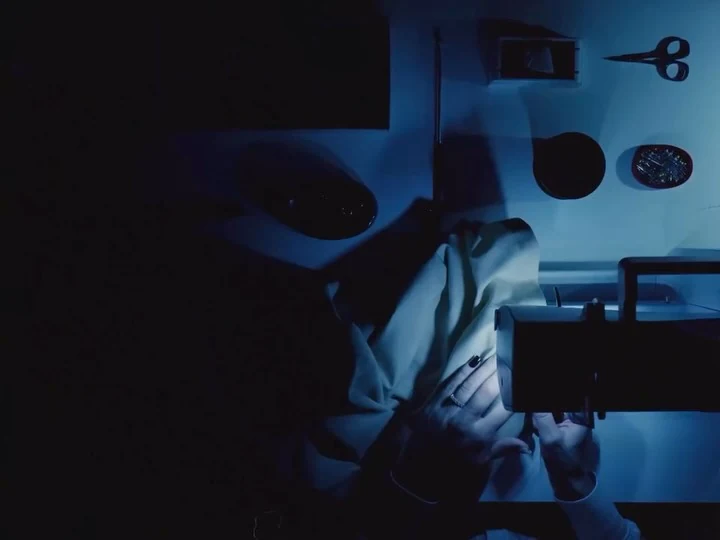 Diana working at her sewing machine in blue light