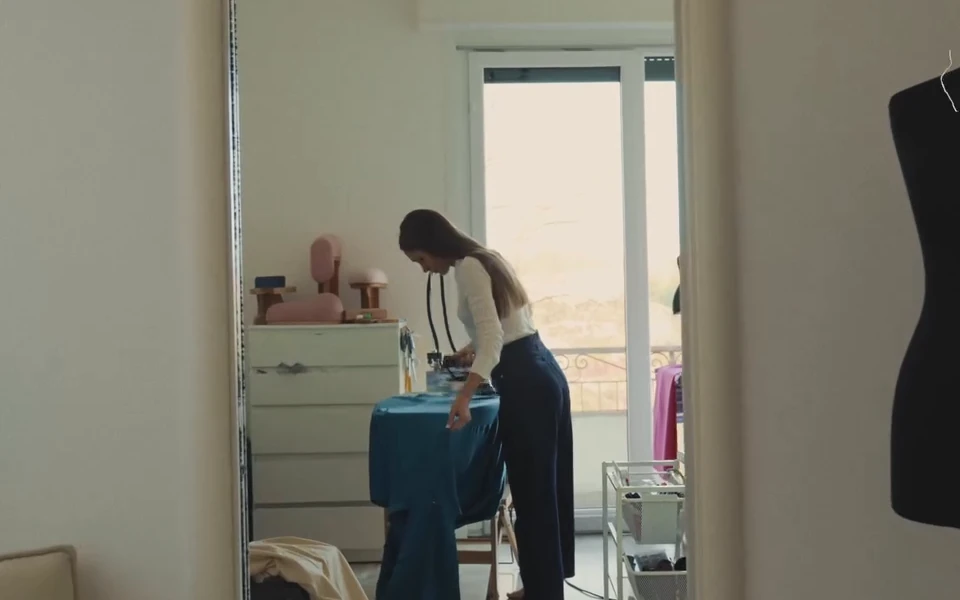 Diana working on a garment beside the tall window of her studio