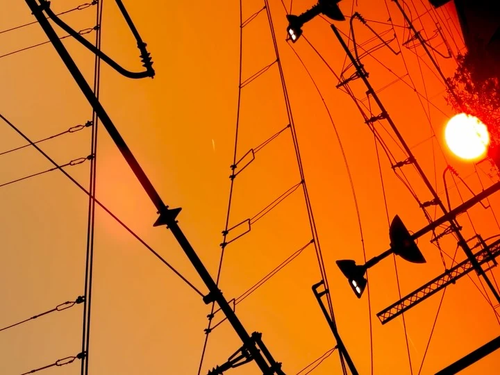 Tram wires and poles against an orange sky