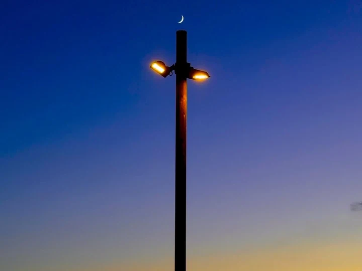 A lit street lamp against deep blue twilight