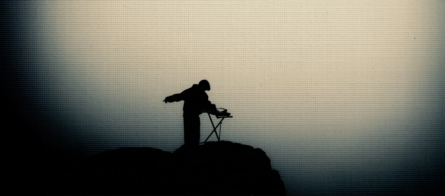 Noah Baine playing a keyboard in silhouette against a foggy landscape