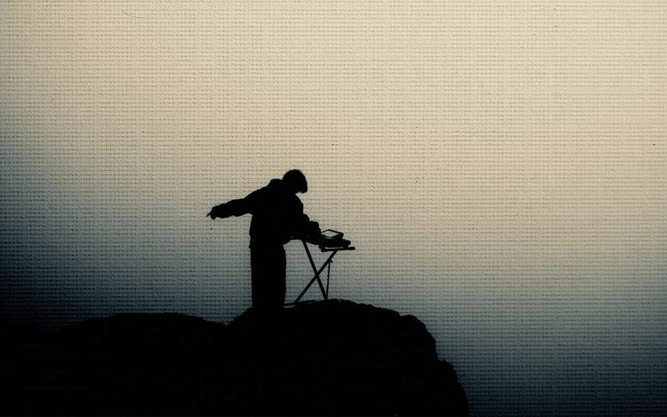 Noah Baine playing a keyboard in silhouette against a foggy landscape
