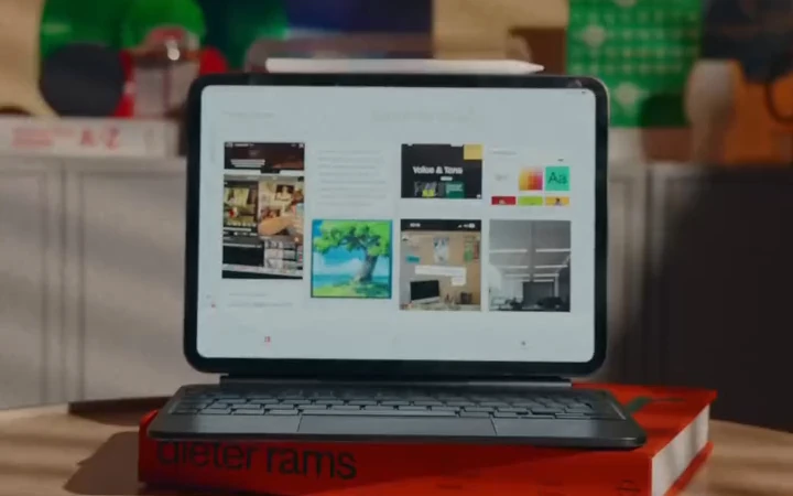 A laptop displaying a collection of visual references, resting on books in warm studio light