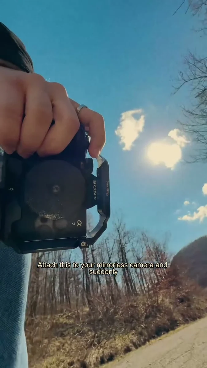 A hand holding a camera fitted with the small lens