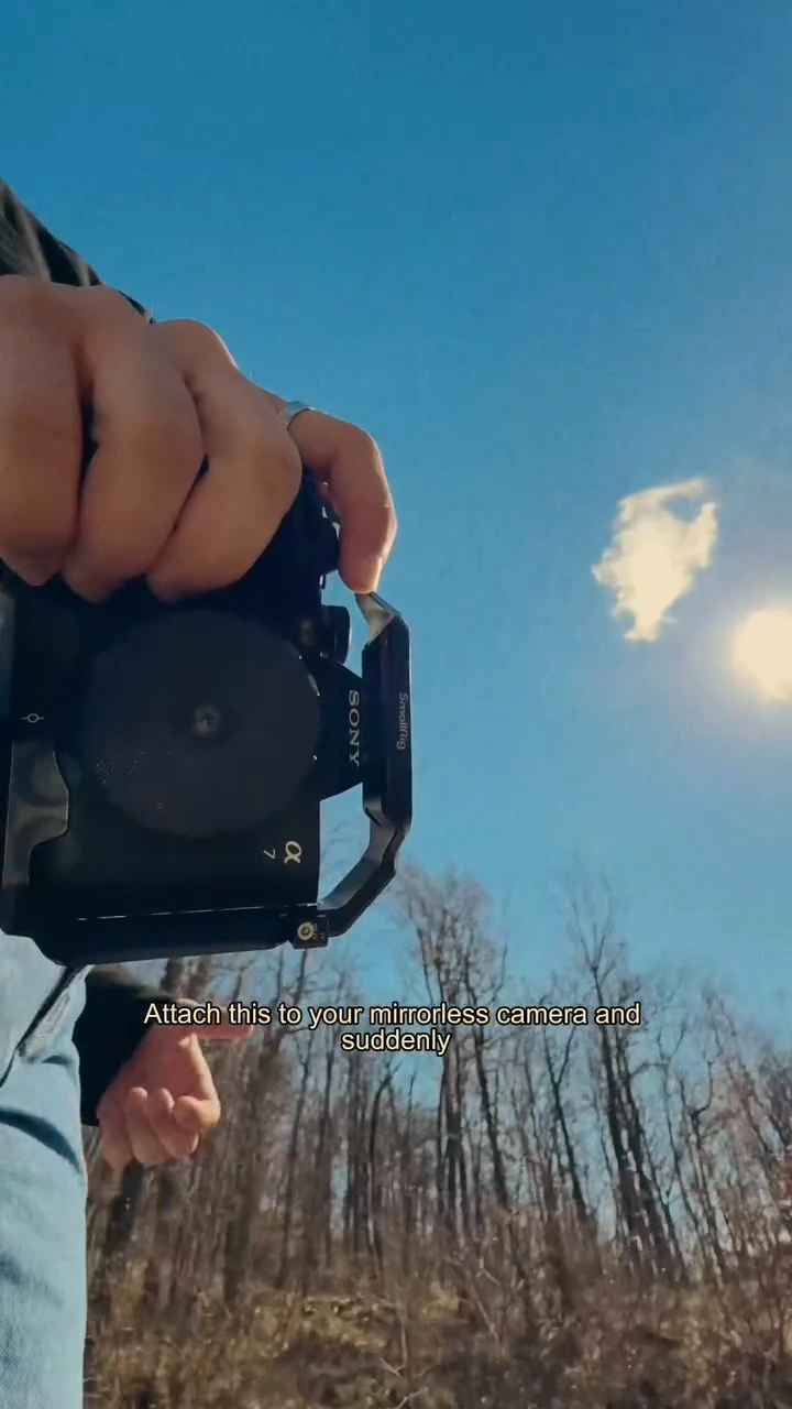 A camera fitted with a small lens, held against a blue sky