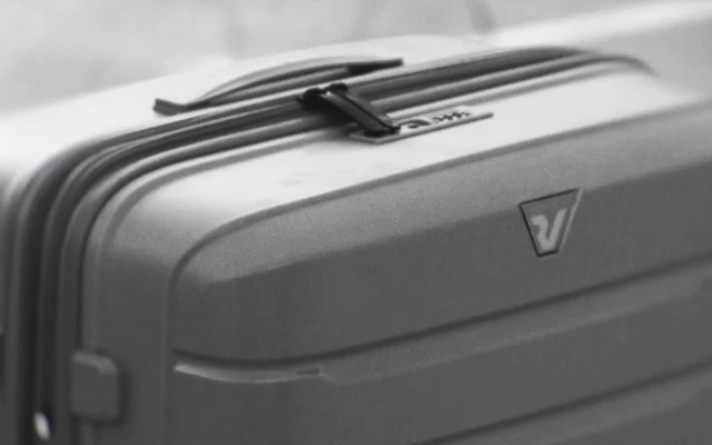 A monochrome close view of the sculpted shell and handle of a Roncato suitcase