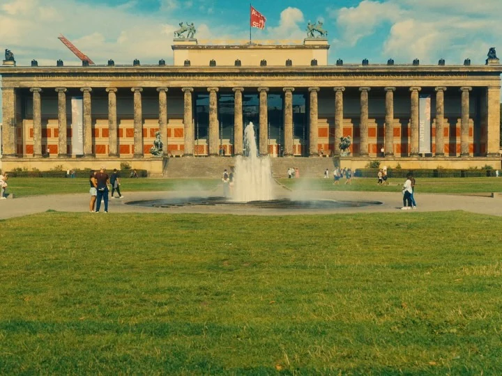 A long pale building behind a green lawn