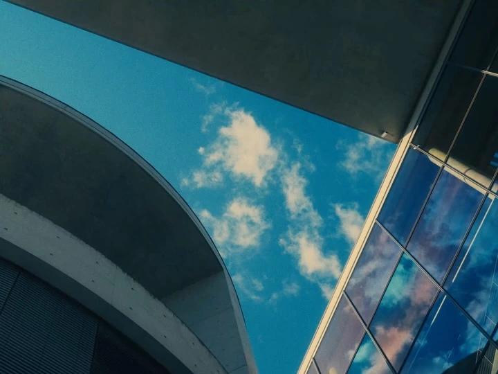 Curved concrete architecture framing blue sky and clouds in Berlin