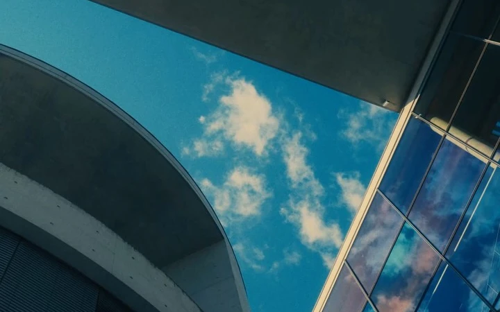 Curved concrete architecture framing blue sky and clouds in Berlin