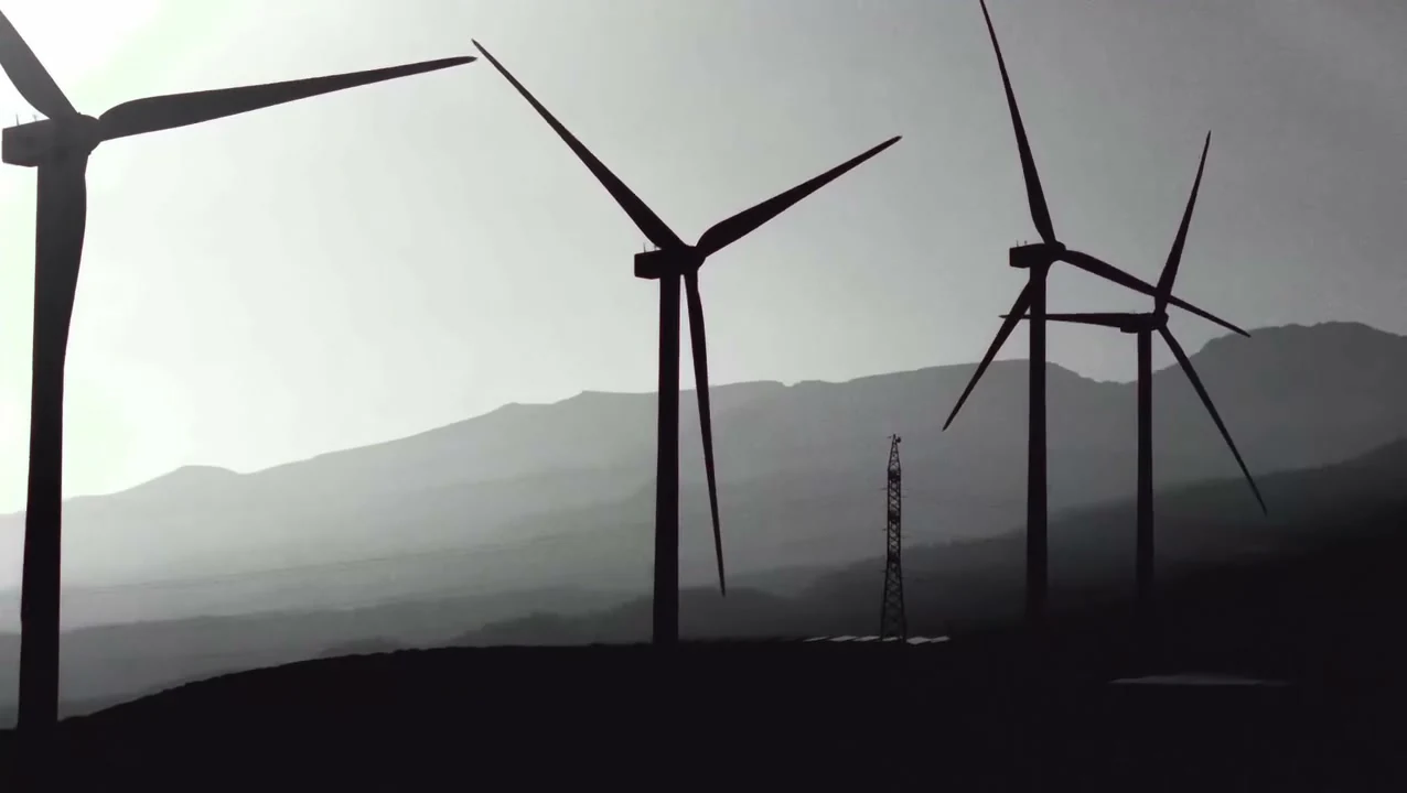 Wind turbines above a hazy mountain landscape