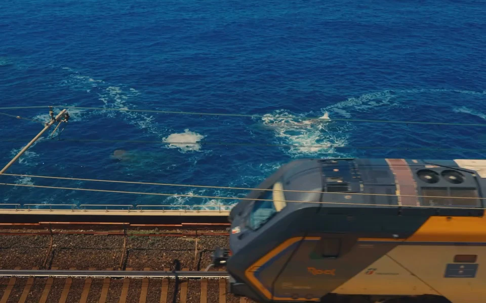 A train passing beside a deep blue sea