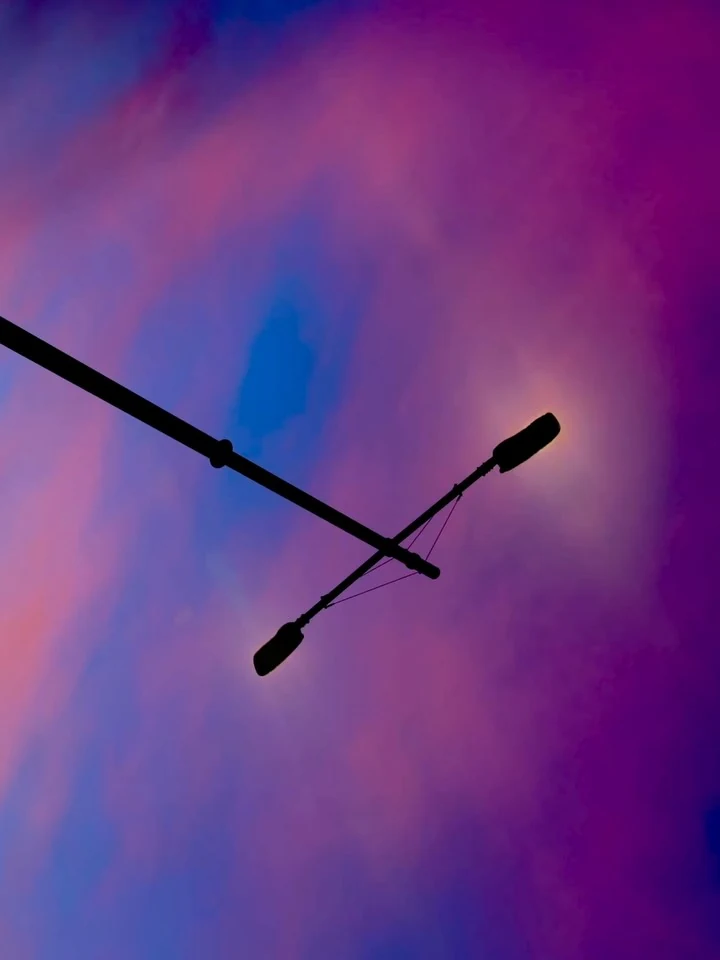 Two street lamps against pink and blue clouds